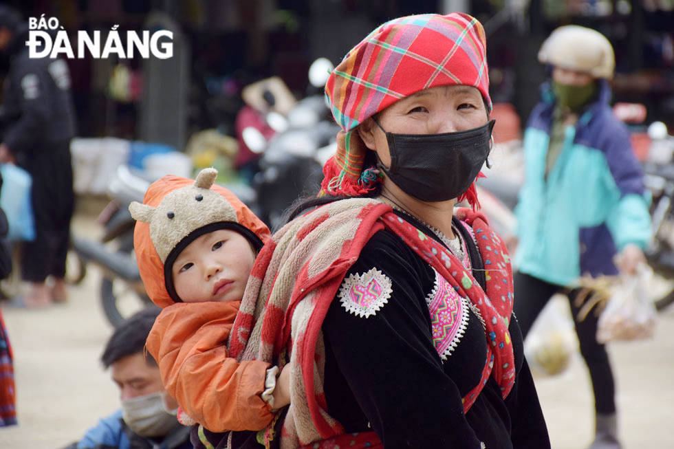 A Mong ethnic minority mother carrying her baby on back to the market. 