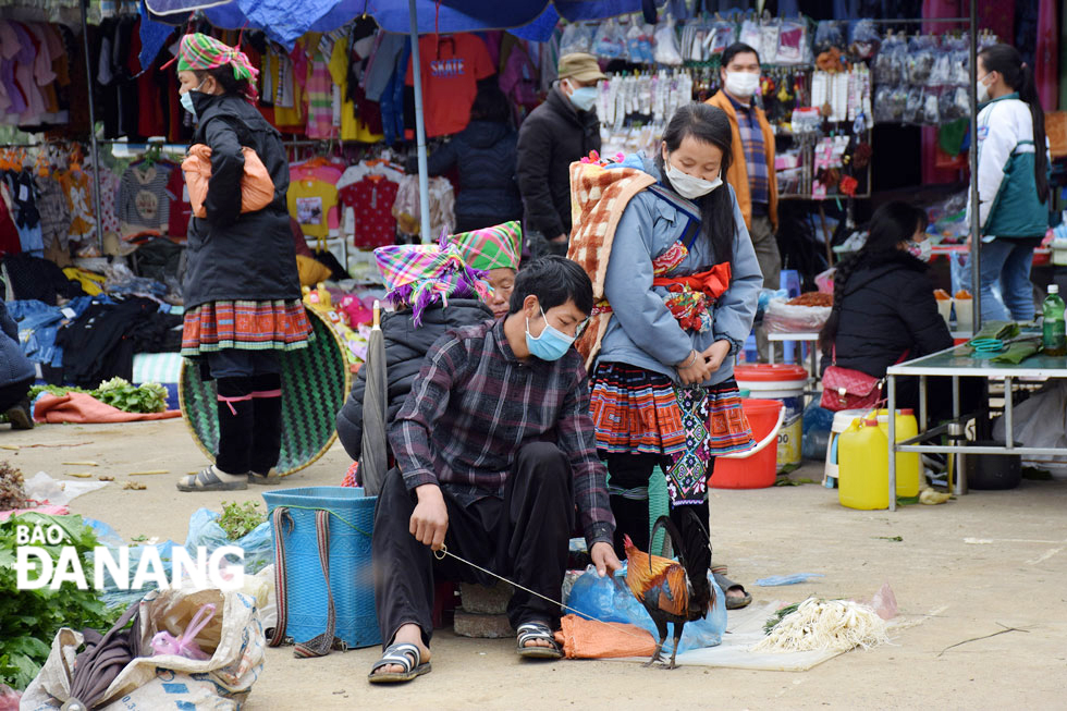 A young ethnic minority couple selling a wild chicken at the market.