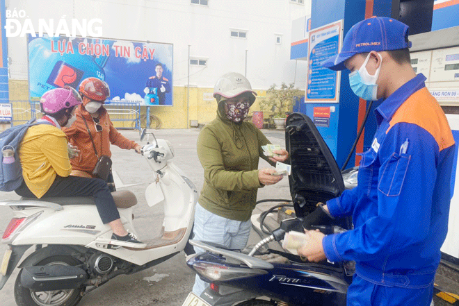 A motorcyclist has her vehicle re-filled at the filling station on Nguyen Van Thoai Street, Ngu Hanh Son District on the afternoon of March 1. Photo: QUYNH TRANG