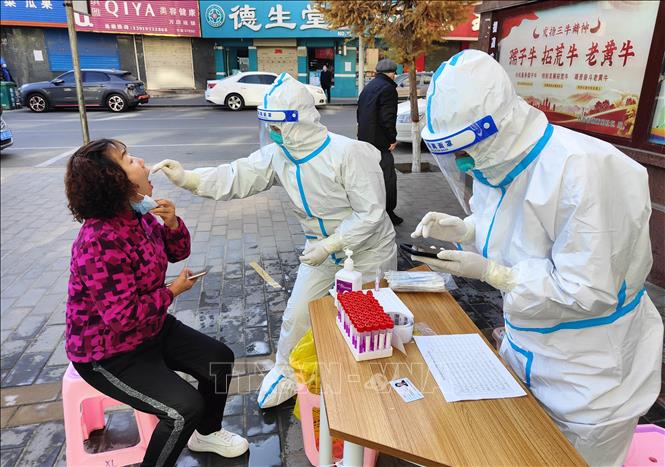 Nhân viên y tế lấy mẫu xét nghiệm COVID-19 cho người dân tại tỉnh Cam Túc, Trung Quốc. Ảnh: AFP/TTXVN