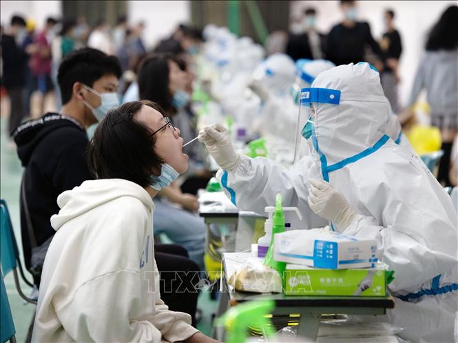 Nhân viên y tế lấy mẫu xét nghiệm Covid-19 cho học sinh tại Thượng Hải, Trung Quốc, ngày 14-3-2022. Ảnh: THX/TTXVN