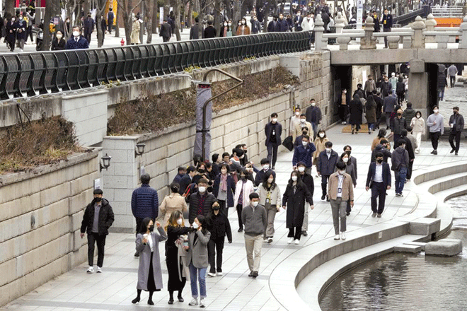 Người dân mang khẩu trang khi đi lại trên đường phố Seoul của Hàn Quốc ngày 17-3. Ảnh: AP
