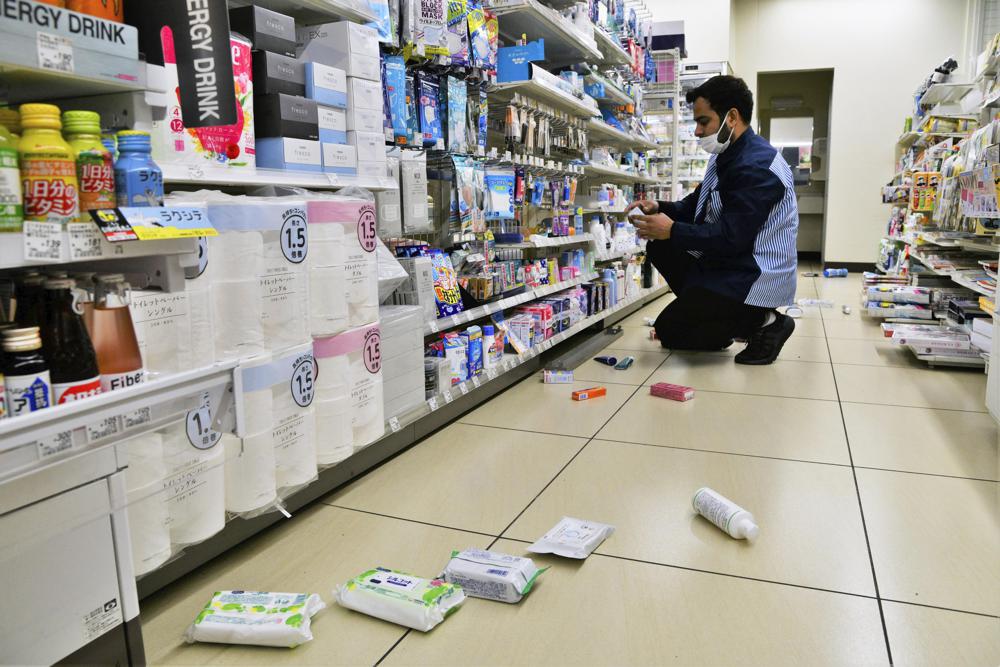 Nhân viên dọn dẹp hàng hóa rơi khỏi kệ tại một cửa hàng tiện lợi ở Fukushima sau trận động đất. Ảnh: AP