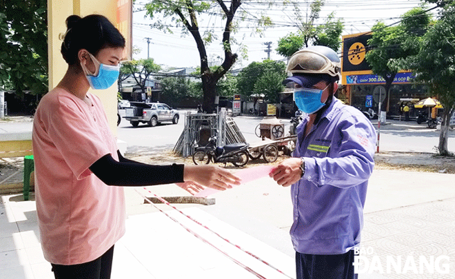 A voluteering female student (left) has been active in supporting the Mobile Medical Station No. 1 located in Hoa Khanh Bac Ward, Lien Chieu District to hand Home Isolation Completion Certificate to a family member of a patient with COVID-19. Photo: DAC MANH