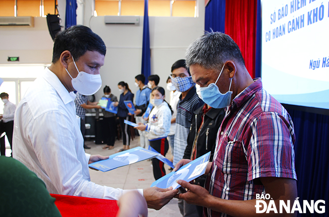 Standing Vice Chairman of the municipal People's Committee Ho Ky Minh giving social insurance books and health insurance cards to people in Ngu Hanh Son District. Photo: XUAN DUNG