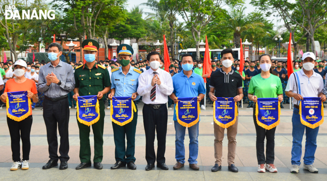 Director of the Da Nang Department of Culture and Sports Pham Tan Xu (centre) presenting souvenir flags to participating units in the Olympic Run Day for Public Health 2022. Photo: TRUONG KY