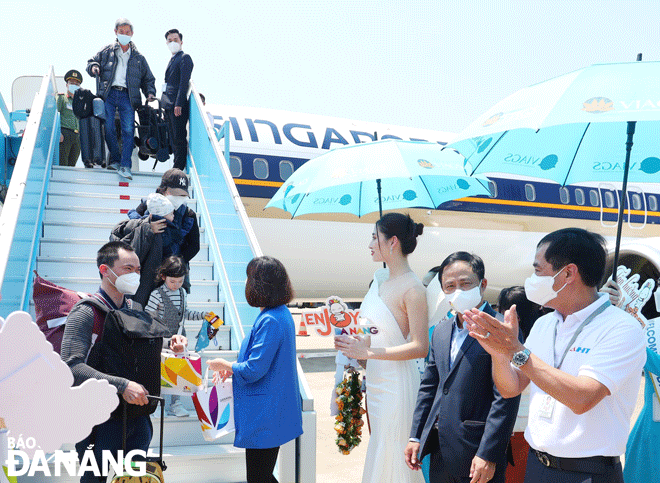 The celebrations for the resumption of international flights in Da Nang open up great opportunities to develop tourism, trade and services in the city. IN THE PHOTO: Leaders of the municipal Department of Tourism presenting welcome flowers and gifts to the first international visitors to the city at Da Nang International Airport on March 27. Photo: THU HA