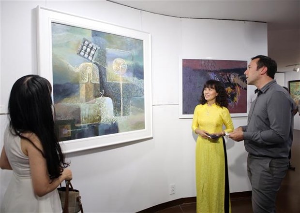 Foreign visitors admire the artworks on display at the ‘Reunion’ exhibition. Photo: VNA