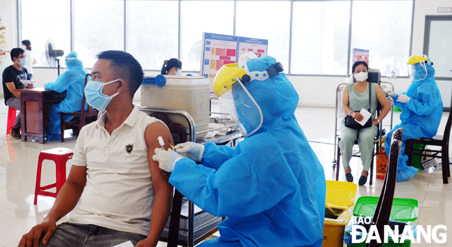 A health care worker administering a COVID-19 vaccine to a man in mask in Ngu Hanh Son District. Photo: PHAN CHUNG