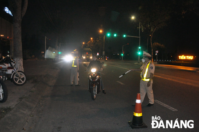 Traffic police officers stopping motorbike drivers for administrative inspection on Pham Hung Street in Hoa Xuan Ward, Cam Le District.