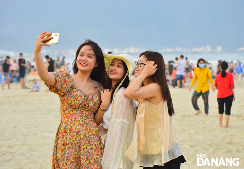 Young people excitedly check-in by the beach.