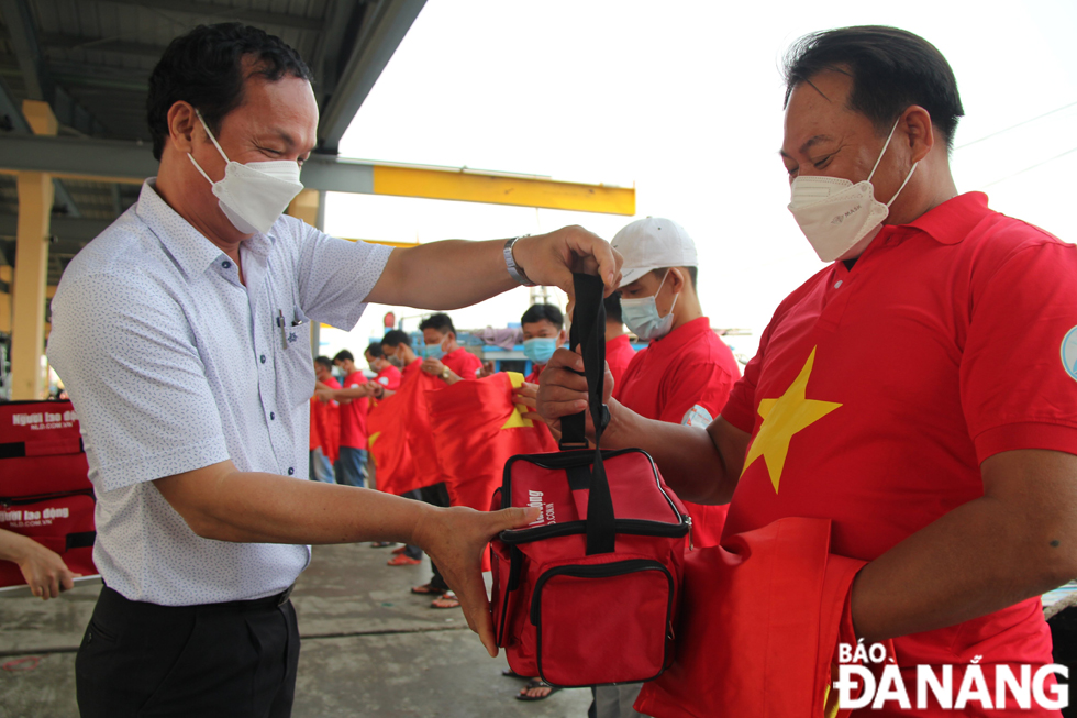 Ông Phan Văn Mỹ, Phó Giám đốc Sở Nông nghiệp và Phát triển nông thôn Đà Nẵng trao cờ Tổ quốc và túi y tế cho ngư dân trong sáng 12-4. Ảnh: VĂN HOÀNG