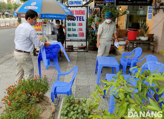 Lực lượng chức năng phường An Hải Tây (quận Sơn Trà) hỗ trợ người dân thu gọn bàn, ghế  lấn chiếm vỉa hẻ tuyến đường Ngô Quyền.