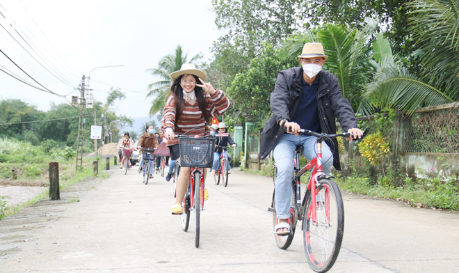 Ho Thi Diem Quynh (left), 22, a fourth-year student at the Da Nang University of Economics introduces the most beauty spots of Hoa Bac to tourists through a bike tour around the countryside. Photo: DAN TAM