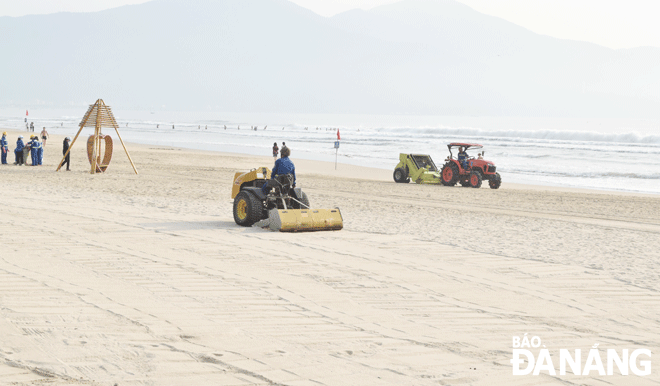 Công ty CP Môi trường đô thị Đà Nẵng huy động phương tiện cơ giới để sàng cát trên bãi biển khu vực Công viên Biển Đông (quận Sơn Trà) nhằm bảo đảm an toàn cho du khách. Ảnh: HOÀNG HIỆP