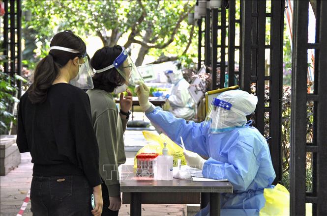 Nhân viên y tế lấy mẫu xét nghiệm COVID-19 cho người dân tại Thượng Hải, Trung Quốc. Ảnh: Kyodo/TTXVN