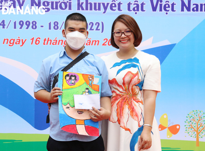 Designer Phuong Nguyen Silk awards the first prize of the painting contest to a male student from the Da Nang Centre for Support and Development of Inclusive Education. Photo: DAN TAM