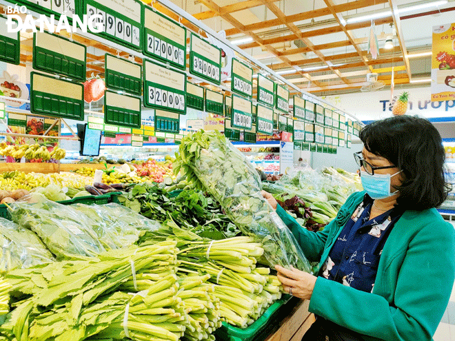 A consumer is seen buying leafy green vegetables grown at the Tuy Loan Organic Vegetables Consumption and Production Service Cooperative which are on sale at the Co.opmart Da Nang supermarket. Photo: QUYNH TRANG