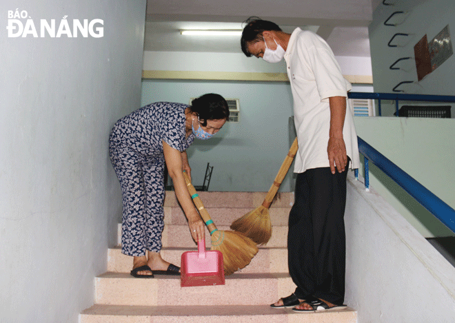 Mrs Dang Thi Ngoc Hoa and her husband take advantage of their spare time to sweep the stairs of apartment F2, Nai Hung 1, Nai Hien Dong Ward, Son Tra District. Photo: THANH TINH