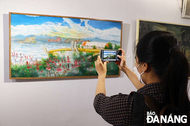  A local visitor takes photos of a nice painting at the exhibition.