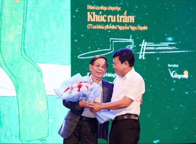 Ông Trần Úc, Chủ tịch UBND thị xã Điện Bàn, tỉnh Quảng Nam (phải) tặng hoa chúc mừng nhà thơ Nguyễn Ngọc Hạnh trong đêm nhạc Khúc ru trầm, ngày 5-5 vừa qua.  (Ảnh do nhân vật cung cấp)