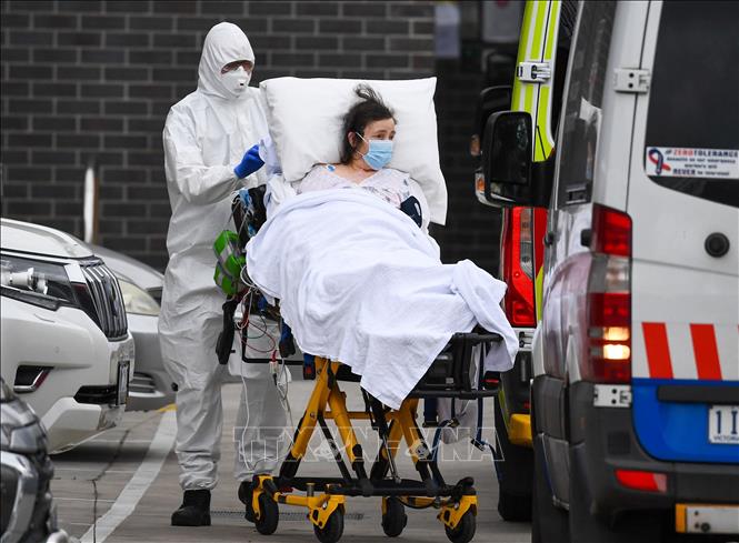 Nhân viên y tế chuyển bệnh nhân COVID-19 lên xe cứu thương tại thành phố Melbourne, Australia. Ảnh: AFP/TTXVN
