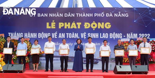 Phó Chủ tịch UBND thành phố Ngô Thị Kim Yến (áo dài xanh, giữa) tặng Bằng khen của Trung ương, địa phương cho các tập thể, cá nhân vì thành tích xuất sắc trong phong trào thi đua lao động an toàn năm 2021. Ảnh: PHAN CHUNG