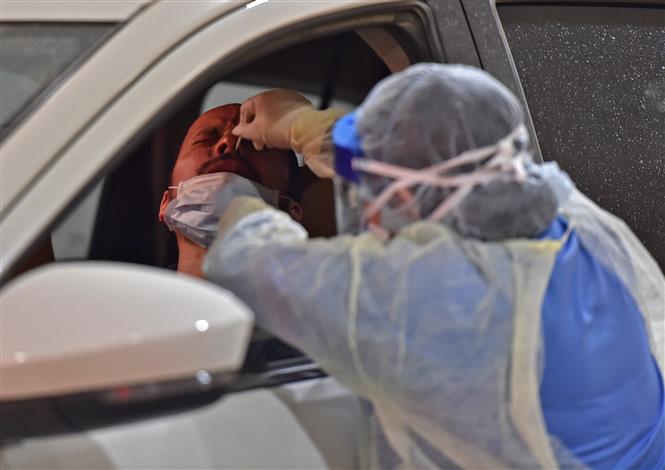 Nhân viên y tế lấy mẫu xét nghiệm Covid-19 cho một tài xế tại Riyadh, Saudi Arabia. Ảnh: AFP/TTXVN
