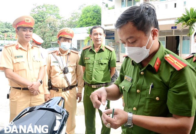 Cán bộ, chiến sĩ Công an xã Hòa Nhơn (huyện Hòa Vang) kiểm tra số khung, số máy phương tiện mô -tô  của người dân đến thực hiện thủ tục. Ảnh: LÊ HÙNG