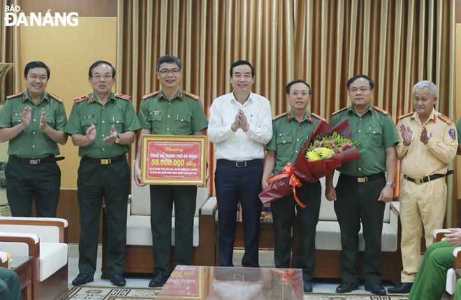 Chairman Chinh (middle) presenting VND 50 million to officers for successfully detaining and prosecuting many offenders for assisting illegal entry into Viet Nam.. Photo: LE HUNG