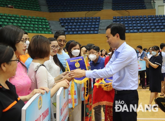 Chairman of the Da Nang Labour Confederation Nguyen Duy Minh presenting souvenir flags to the participating units at the sports festival. Photo: X.S
