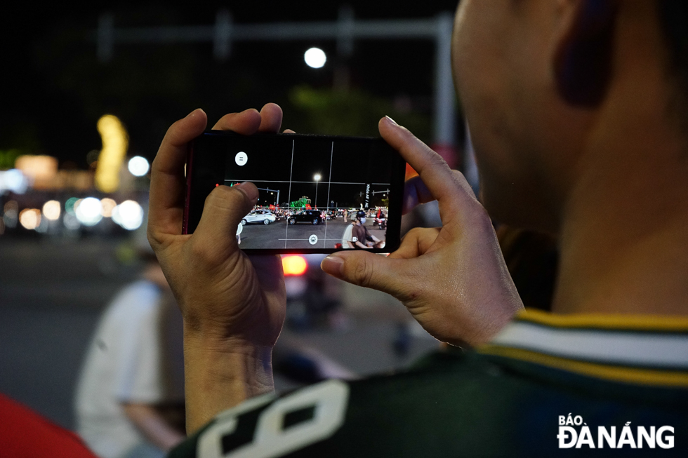 A resident uses his phone to record memorable moments in celebration of Viet Nam's football victory. Photo: T.K