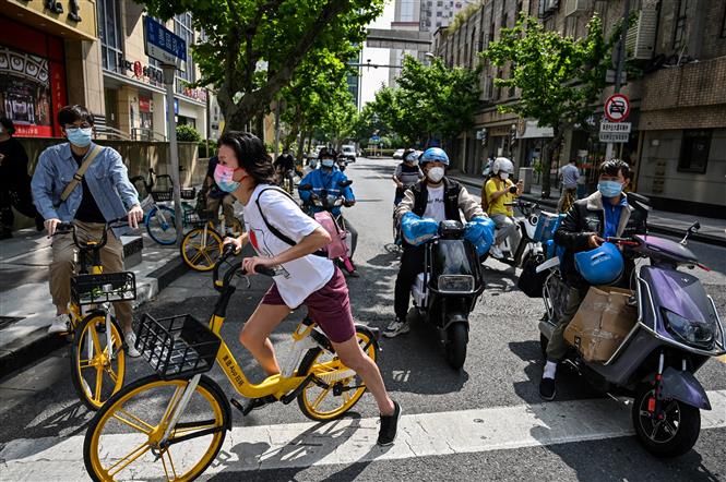 Người dân di chuyển trên một đường phố ở Thượng Hải, ngày 25/5/2022. Ảnh: AFP/TTXVN