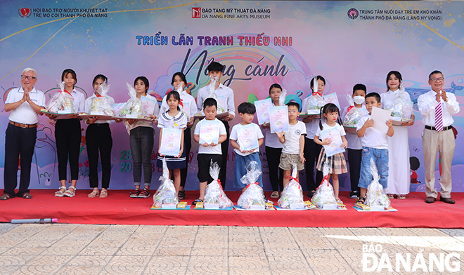 Former Vice Chairman of the Da Nang People's Committee, cum Chairman of the Association for Supporting Orphans and the Disabled Nguyen Hoang Long (first left) and Director of the Da Nang Fine Arts Museum Ha Thanh Van (first right) giving gifts and certificates of attendance to participating children. Photo: Xuan Dung