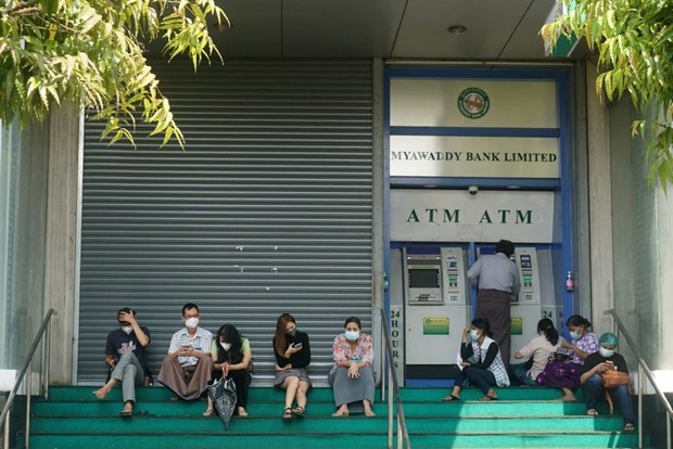 People wait to withdraw money from an ATM outside a branch of Myawaddy Bank in Yangon on February 23. (Photo: AFP/VNA)