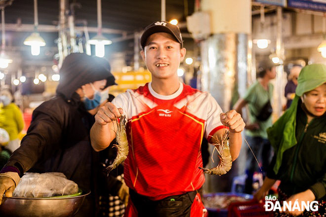 A small merchant invites customers to buy fresh shrimps