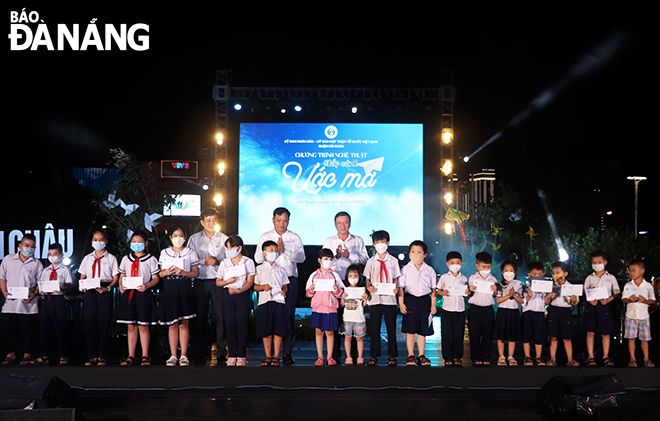 Head of the municipal Party Committee Mass Mobilisation Board Le Van Trung (10th right) and child recipients