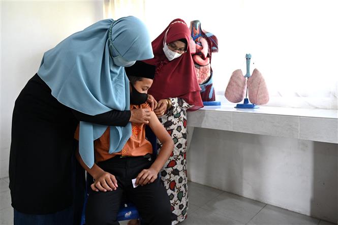 Nhân viên y tế tiêm vaccine phòng COVID-19 cho học sinh tại Darul Imarah, gần Banda Aceh, Indonesia. Ảnh: AFP/TTXVN