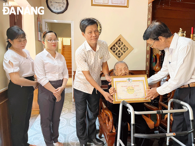 Trưởng ban Đại diện Hội Người cao tuổi thành phố Phạm Quý (giữa) đến thăm, trao quà mừng thọ tròn 100 tuổi cho cụ Ngô Thị Kinh (phường Hòa Thọ Đông, quận Cẩm Lệ) nhân dịp kỷ niệm 81 năm ngày Truyền thống người cao tuổi Việt Nam (6-6-1941 - 6-6-2022)