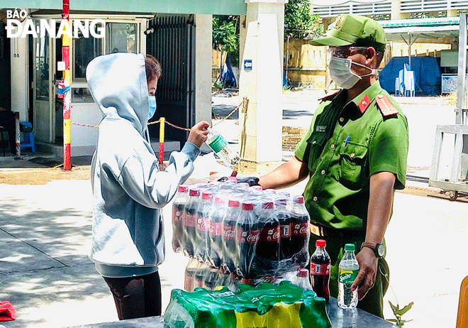 Trung úy Mai Tấn Phu (bên phải) hỗ trợ trao nước uống và cơm cho sinh viên tại Khu ký túc xá phía tây thành phố trong thời điểm cả thành phố thực hiện giãn cách xã hội.  Ảnh: C.A	