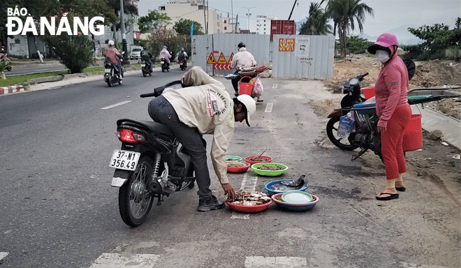 Một người dân buôn bán hải sản lấn chiếm lòng đường Nguyễn Tất Thành (quận Thanh Khê). Ảnh: ĐẮC MẠNH