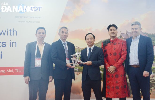 Deputy Director of the Da Nang Department of Tourism Nguyen Xuan Binh (centre) hands over the Routes Asia 2023 hosting logo to the Thai representative (2nd, left). Photo: THU HA