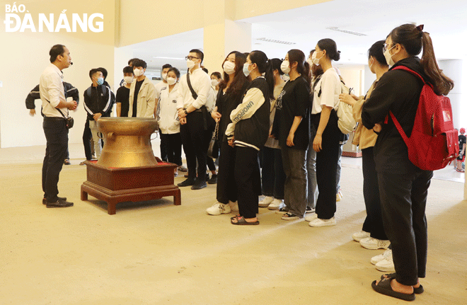 A museum guide (left) introducing artifacts on display at the Museum of Da Nang to students of the city-based Duy Tan University. Photo: VAN HOANG