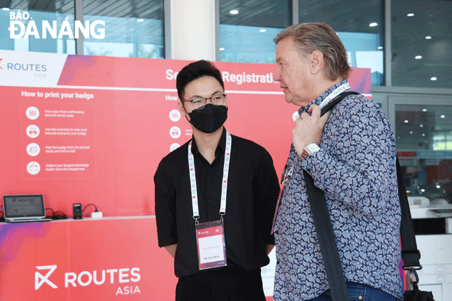 Volunteer Pham Van Nhat (left) is talking with a delegate attending Routes Asia 2022. Photo: THU UYEN