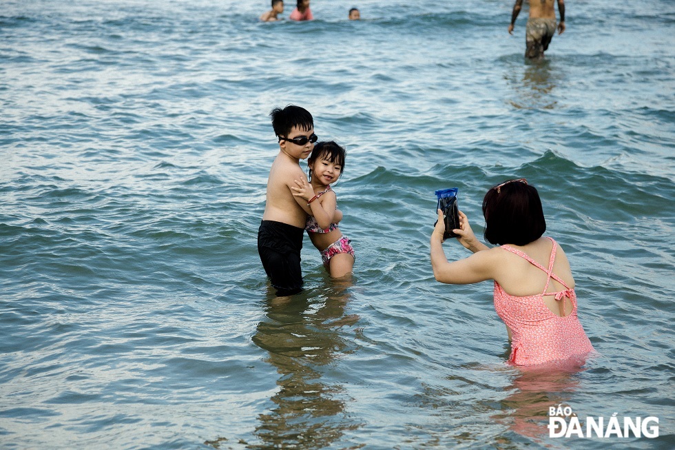 A mother recording beautiful moments of her children at the My Khe Beach.