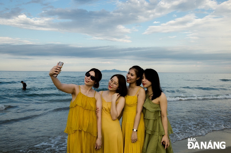 A group of tourists together saving beautiful moments on the Da Nang beach.