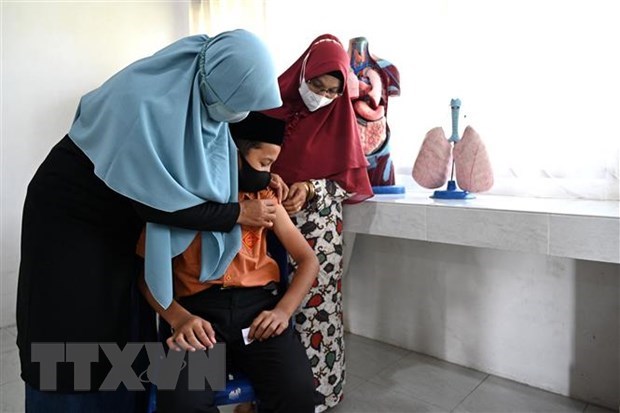 Health workers inject COVID-19 vaccine to a student in Indonesia. (Photo: AFP/VNA)