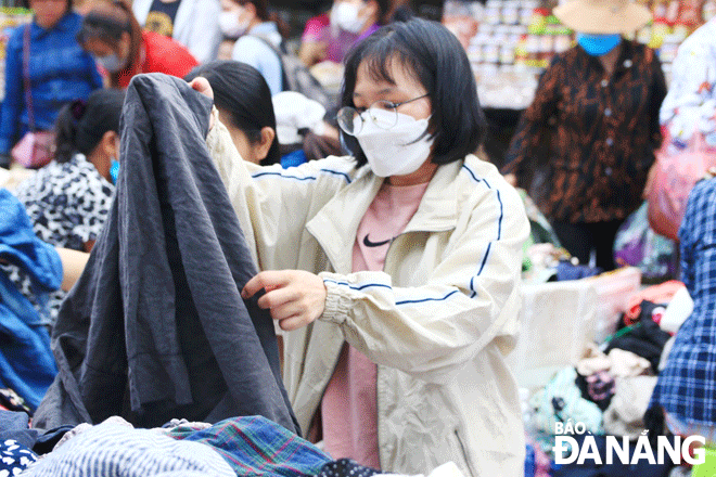 A young woman is shopping second hand clothing at the Con Traditional Market. Photo: CHIEN THANG