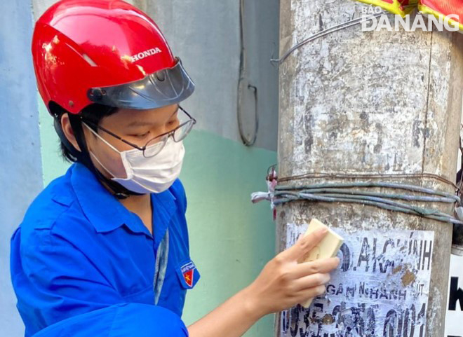 Đoàn viên thanh niên phường Hòa Thuận Đông (quận Hải Châu) xóa quảng cáo rao vặt trên các trụ điện.