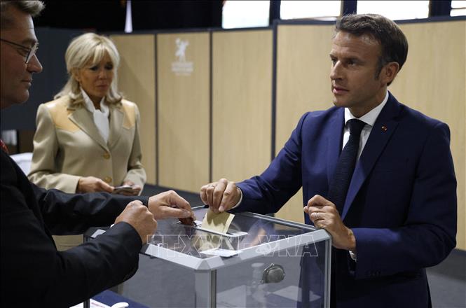 Tổng thống Pháp Emmanuel Macron (phải) cùng phu nhân Brigitte Macron bỏ phiếu bầu cử Quốc hội Khóa XVI tại Le Touquet, ngày 12/6/2022. Ảnh: AFP/TTXVN
